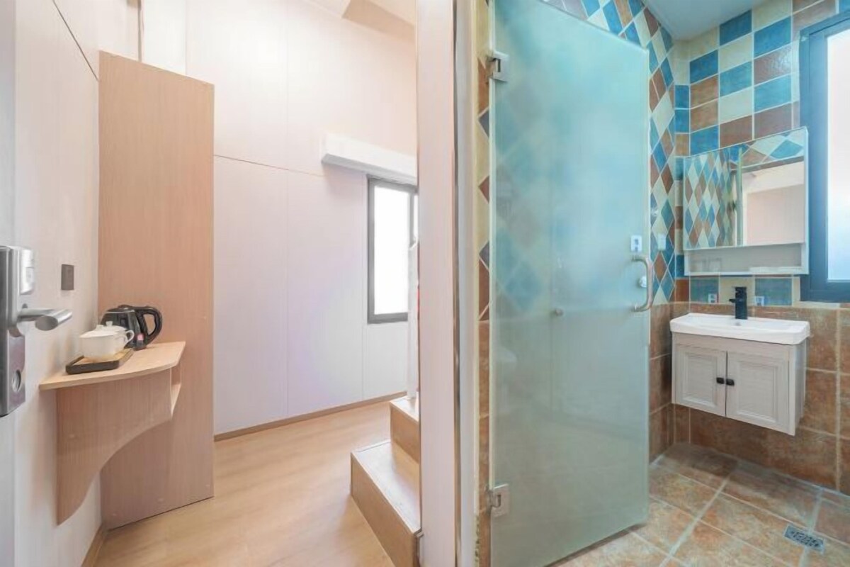 Ein modernes Badezimmer mit Duschabtrennung aus Glas, einem Waschbecken mit Spiegel und einer gefliesten Rückwand.