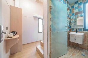 Ein modernes Badezimmer mit Duschabtrennung aus Glas, einem Waschbecken mit Spiegel und einer gefliesten Rückwand.