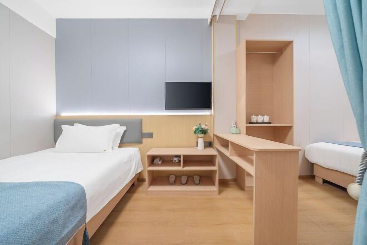 Ein modernes Hotelzimmer mit einem Bett, einem Schreibtisch und einem an der Wand montierten Fernseher.