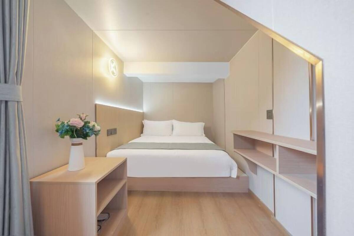 Un dormitorio moderno con cama, mesita de noche y lámpara de pared.