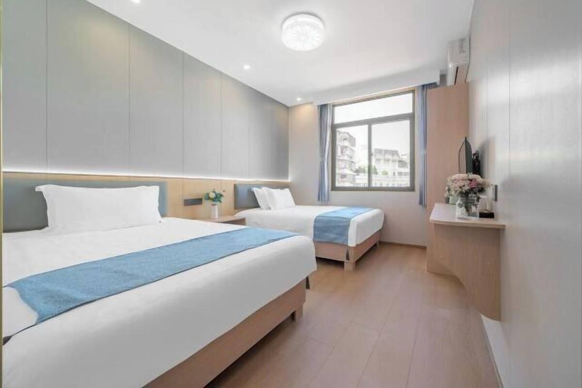 Habitación de hotel con dos camas, una mesita de noche, una ventana con vistas y un televisor montado en la pared.