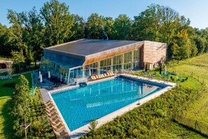 Ein modernes Gebäude mit Schwimmbad, umgeben von üppiger Vegetation.