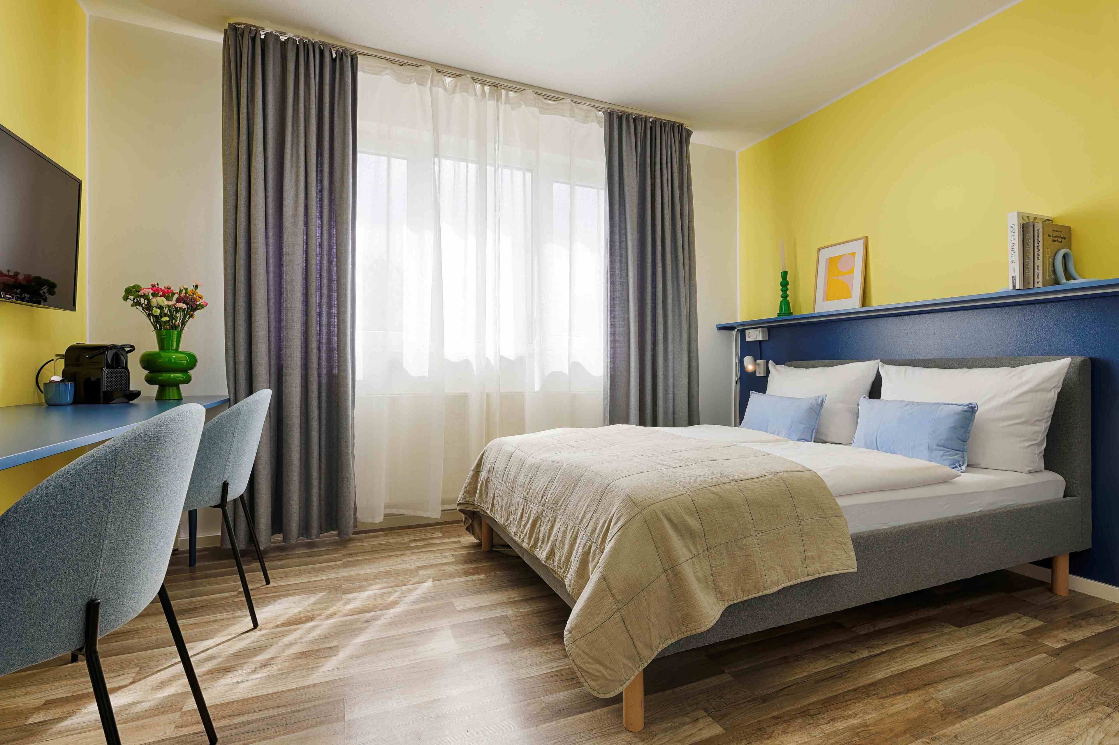 A bedroom with a bed, a desk, and chairs.
