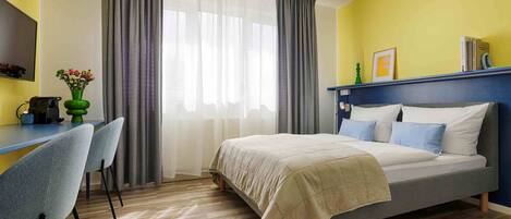 A bedroom with a bed, a desk, and chairs.