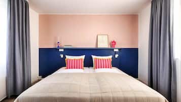 Un letto matrimoniale con una coperta beige e due cuscini a righe rosa e bianche.