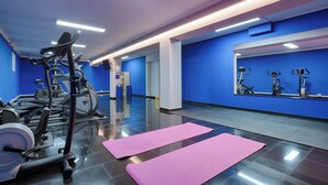 A modern gym with exercise equipment, a large mirror, and a clean, blue and white color scheme. - homie hotel max apart (Fuerth)