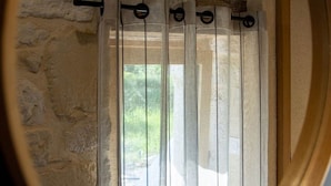 Eine Steinsäule mit einem Fenster, an dem eine Gardinenstange und Vorhänge angebracht sind.