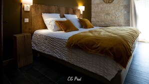 Ein Schlafzimmer mit einem Holz-Kopfteil, weißer Bettwäsche und zwei Wandleuchten.