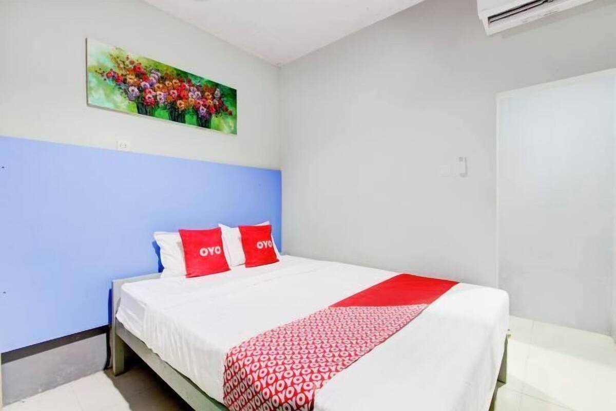 Une chambre à coucher avec un lit, un tableau accroché au mur et une porte blanche.