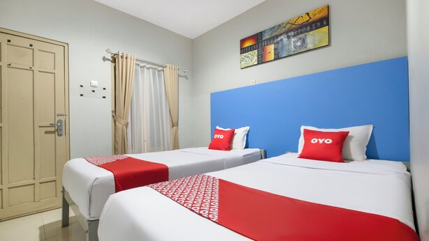 Ein Hotelzimmer mit zwei Betten, jeweils mit einer roten und weißen Tagesdecke und passendem Kissen.