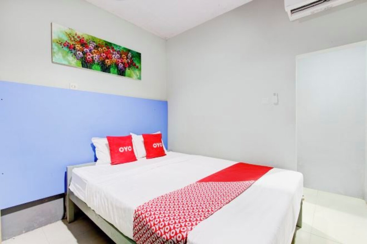 Une chambre à coucher avec un lit, un tableau accroché au mur et une porte blanche.