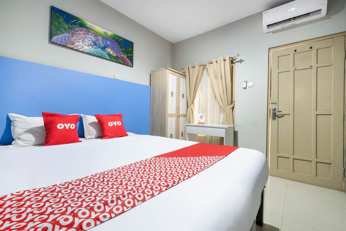 Une chambre d’hôtel avec un lit, un bureau, une armoire et un tableau au mur.