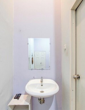 Ein Badezimmer mit einem weißen Waschbecken, einem Spiegel und einer Tür.