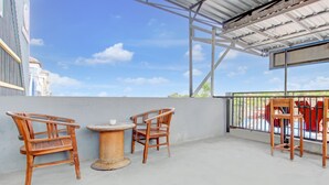 A covered outdoor seating area with two wooden chairs and a small round table. - Hotel O Prawirotaman Near Keraton Yogyakarta Formerly Paris Guesthouse (Sewon)
