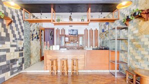 A modern kitchen with a wooden island, stools, and a TV. - Hotel O Prawirotaman Near Keraton Yogyakarta Formerly Paris Guesthouse (Sewon)