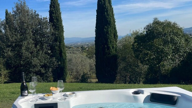 Un bain à remous avec une table pour deux, entouré de verdure et d’arbres.