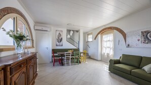 Un vaste espace de vie comprenant un meuble en bois, un canapé vert, une table à manger avec des chaises et un escalier menant à un autre niveau.