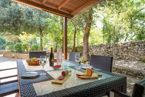 An outdoor dining area with a table set for two, featuring a bottle of wine, glasses, a bowl of fruit, and a selection of cheeses and cured meats. - Nice apartment for 4 guests with WIFI, pool, TV and veranda, close to Siena (Monteriggioni)
