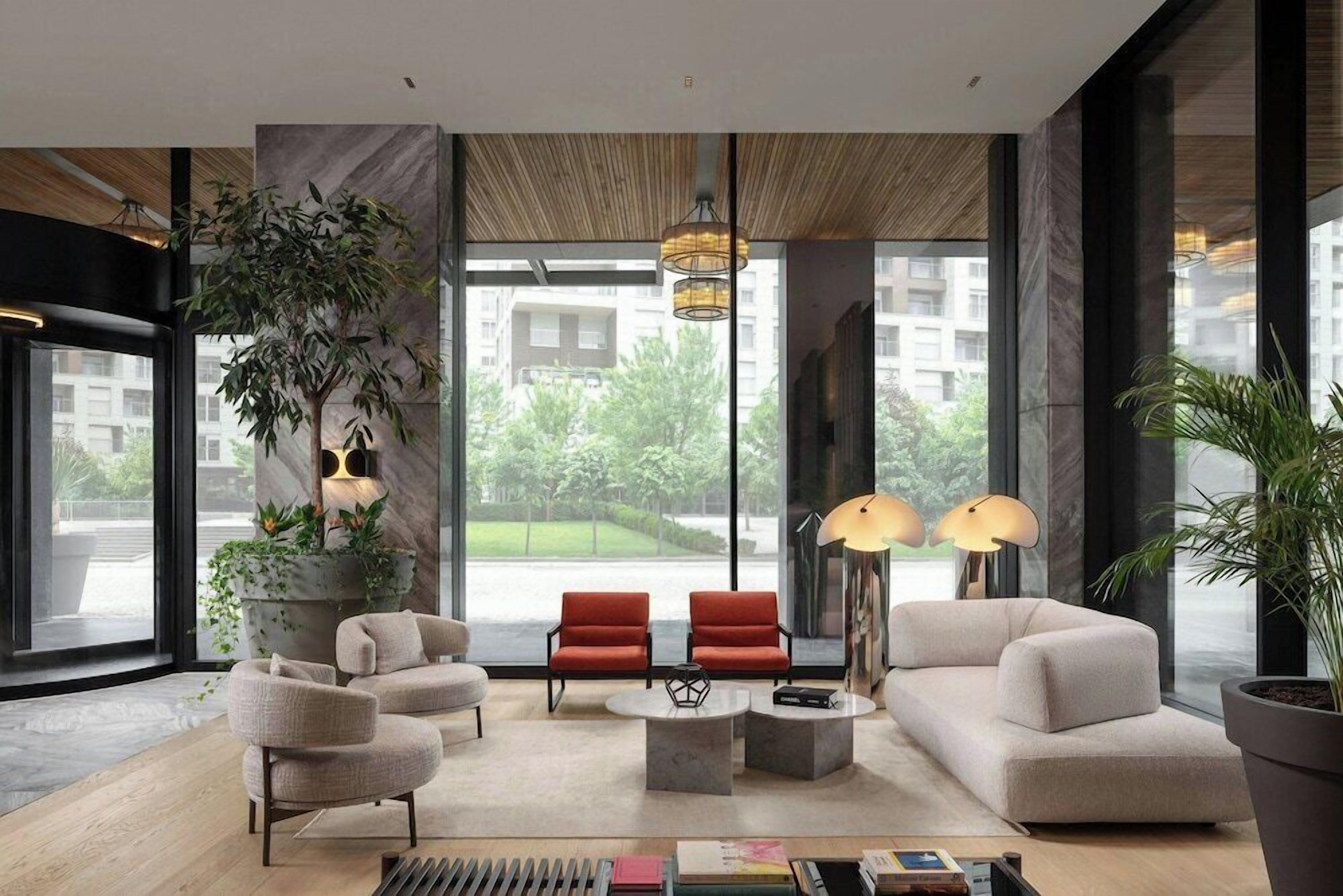 A modern living room with a large window, a potted plant, a sofa, two armchairs, a coffee table, and a floor lamp.