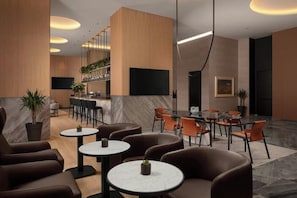 Un hall d’entrée moderne doté d’espaces de détente, d’un bar et d’un écran de télévision.