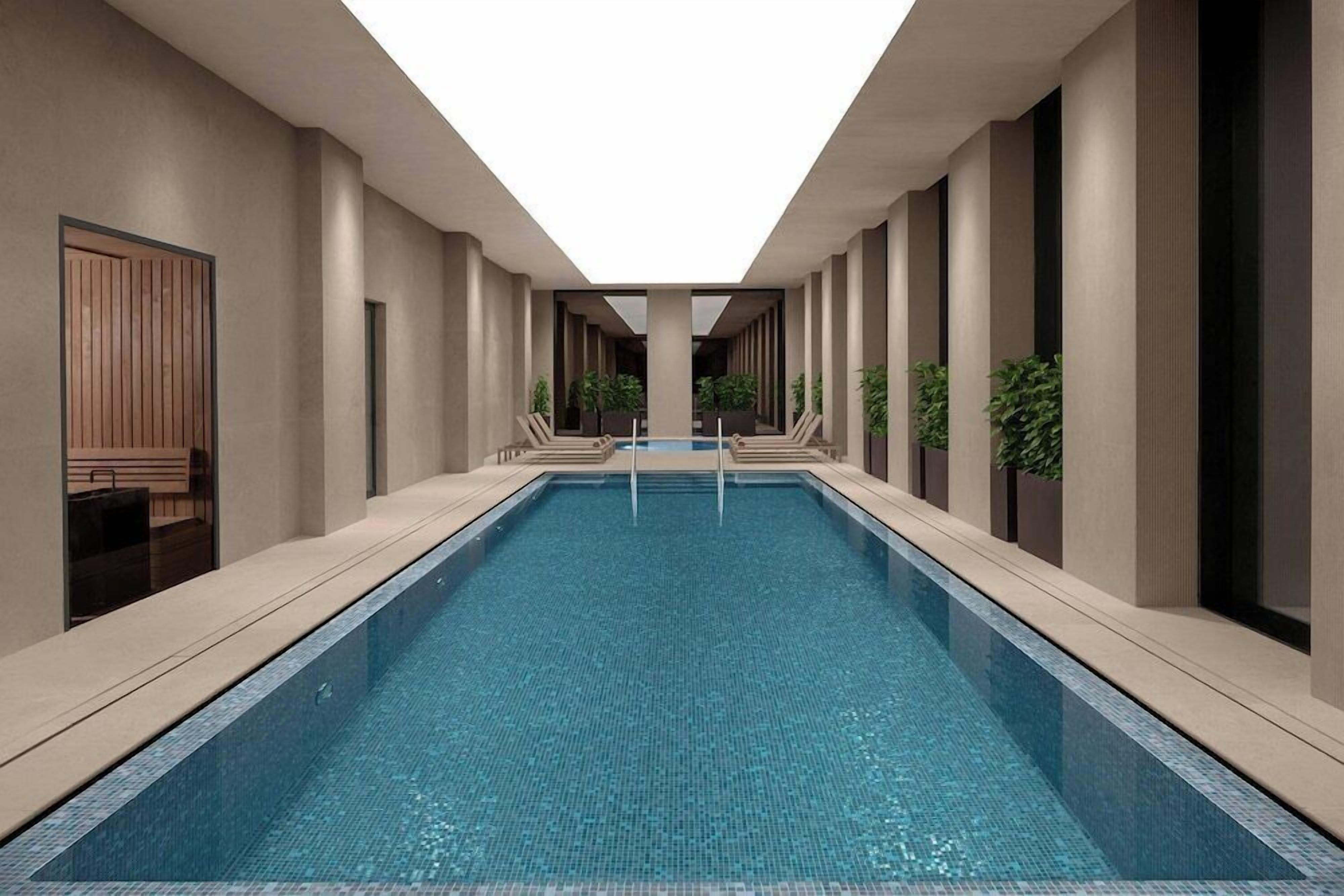 A modern indoor pool with a clear view of the pool area, surrounded by neutral-toned walls and columns.