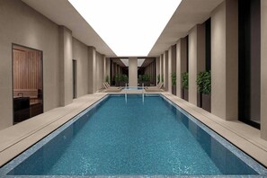 Piscina interior moderna con vista despejada del área de la piscina, rodeada de paredes y columnas en tonos neutros.