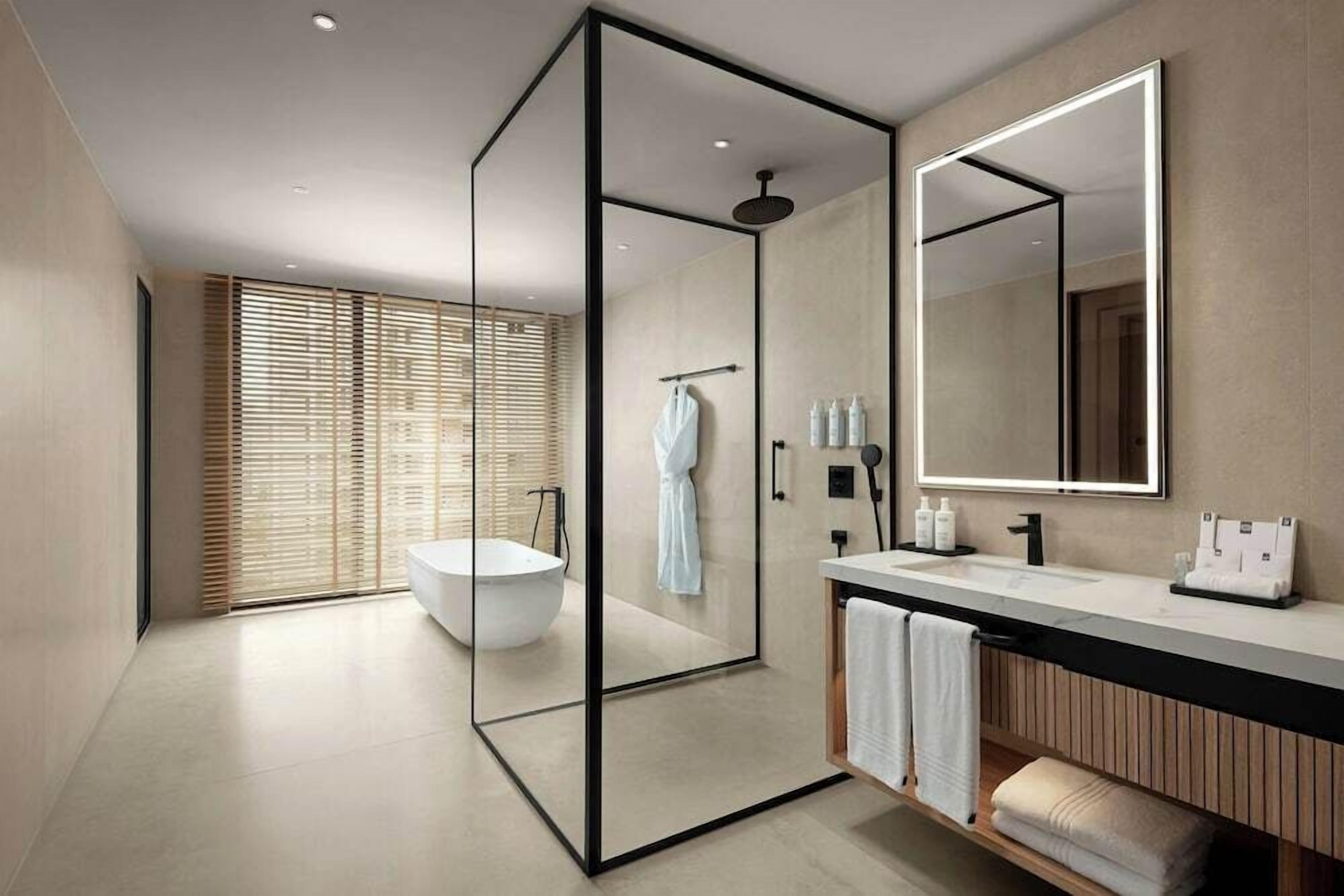 A modern bathroom with a glass-enclosed shower, a freestanding bathtub, a large mirror, and a wooden vanity.