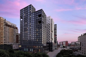 Un immeuble de grande hauteur à la façade structurée en forme de grille, doté de nombreux balcons et d’une cour intérieure.