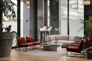 Un salon moderne comprenant un canapé, deux fauteuils, une table basse et un lampadaire.