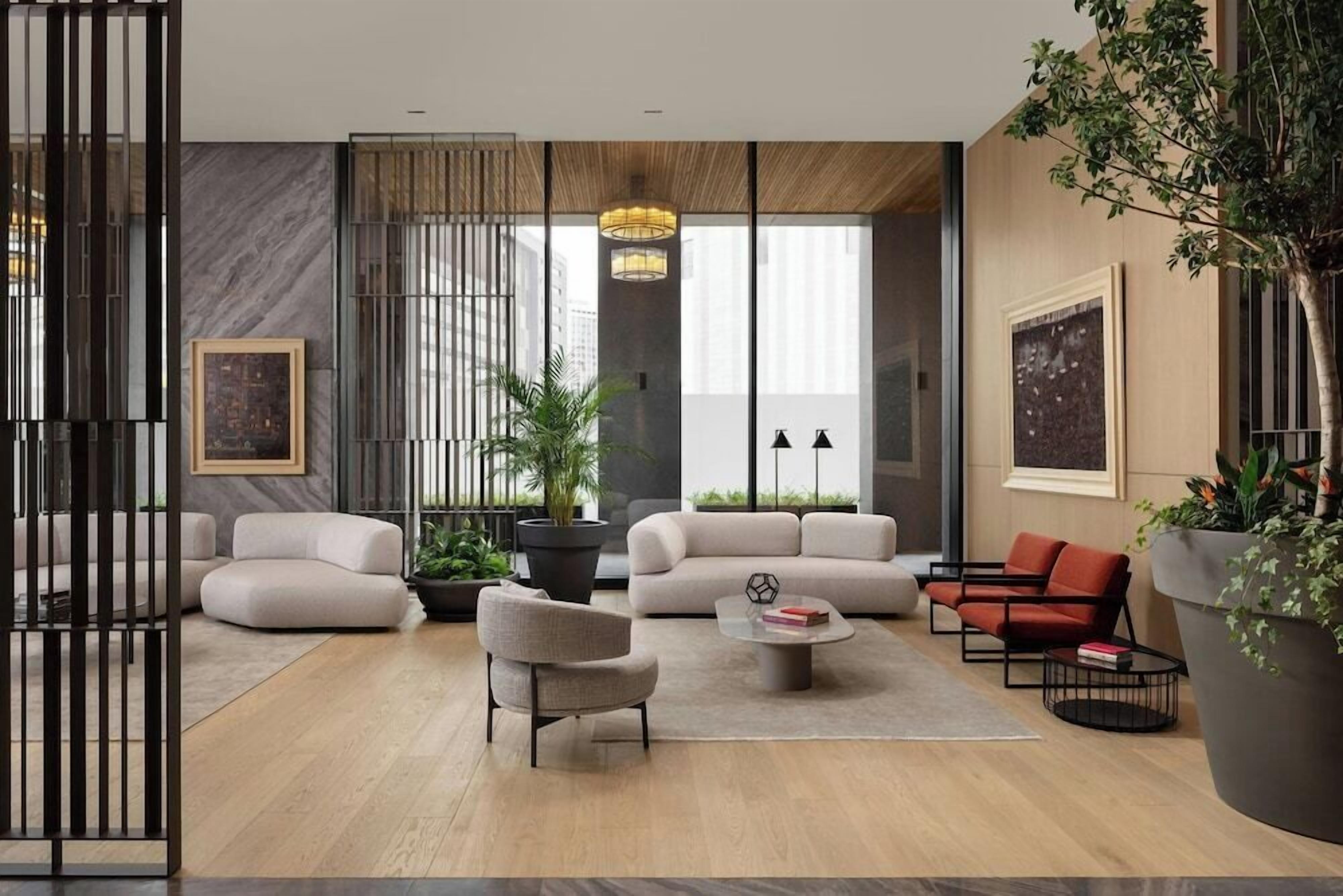 A modern living room with a sofa, armchairs, a coffee table, and a potted plant.