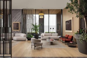 Una sala de estar moderna con un sofá, sillones, una mesa de centro y una planta en maceta.