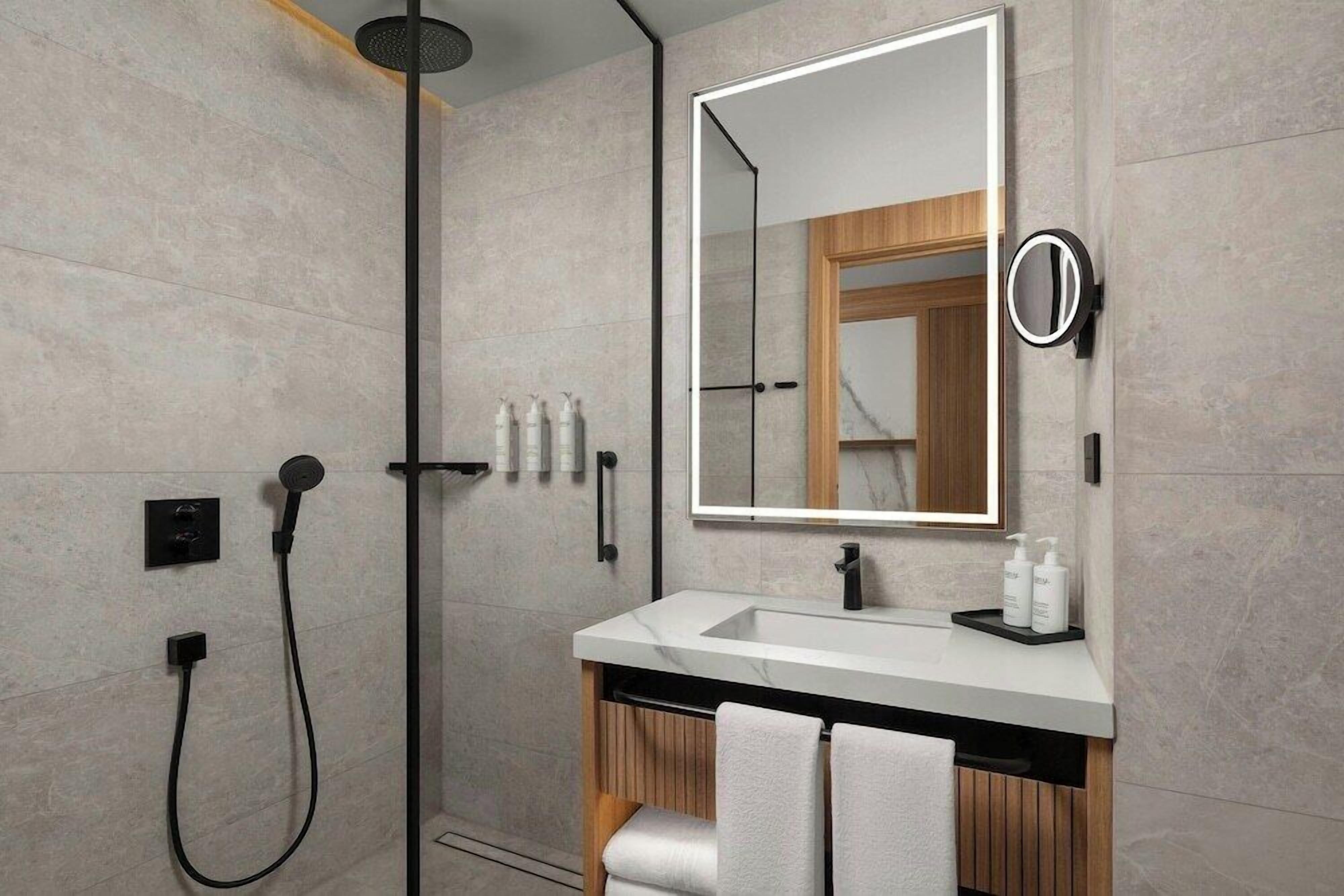 A modern bathroom with a shower, a vanity with a mirror, and a towel rack.