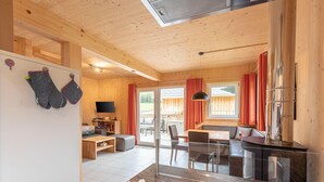 Ein modernes Interieur mit Holzwänden, einem Essbereich, einer Küche und einem Fernseher.