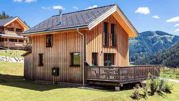 Eine Holzhütte mit einem Balkon, vor einer Bergkulisse gelegen.