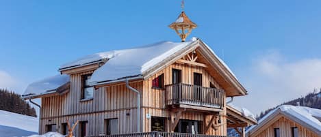 Um chalé de madeira com varanda, rodeado de neve.