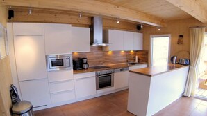 A modern kitchen with white cabinets, stainless steel appliances, and a wooden countertop.