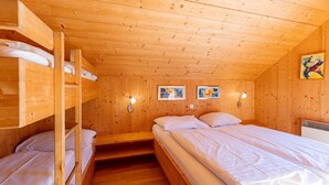 A wooden cabin with bunk beds, a single bed, and two wall-mounted lights.