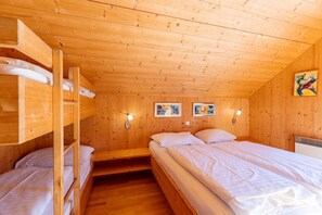 A wooden cabin with bunk beds, a single bed, and two wall-mounted lights.