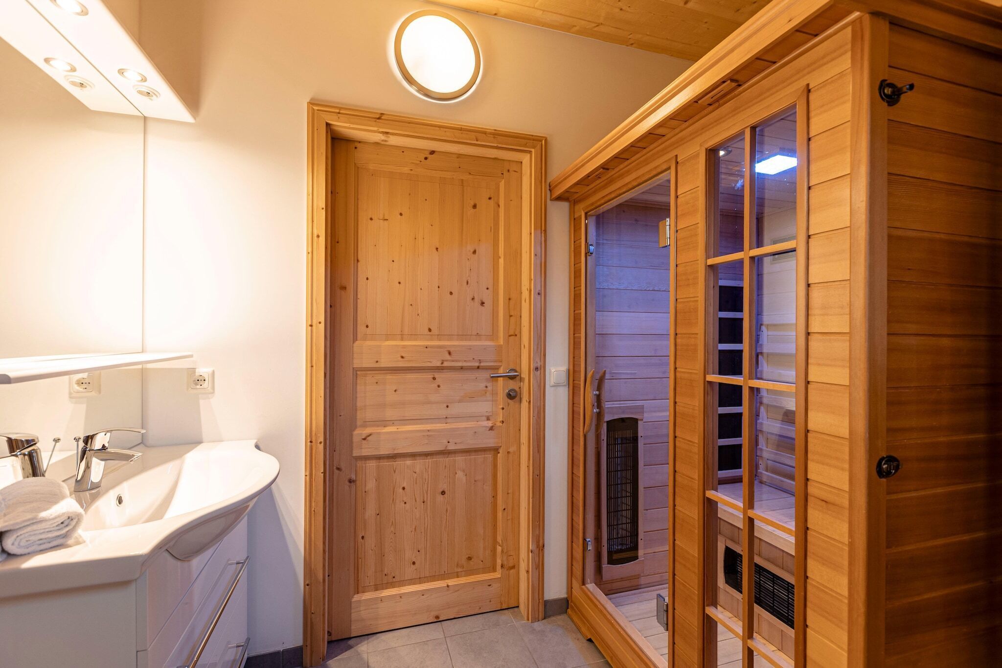 A wooden door, a white sink, and a wooden sauna.