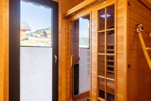Une cabine de sauna en bois dotée d’une porte coulissante en verre, d’un banc en bois et d’une statuette de chien accrochée au mur.