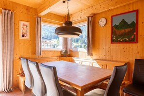 Un interior de madera con una mesa de comedor, sillas, un reloj y un cuadro.