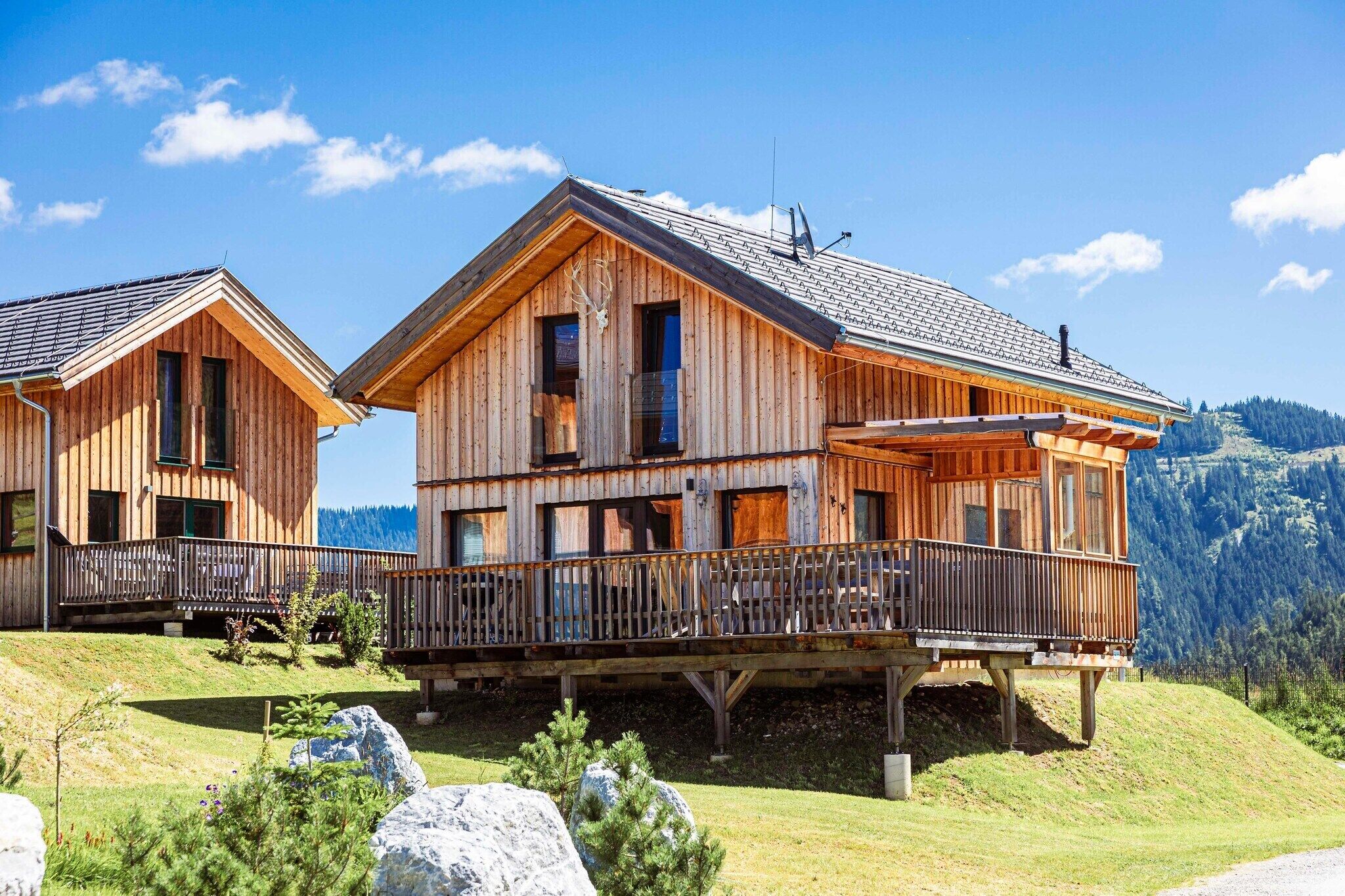 Un chalet en bois doté d’un balcon, d’une terrasse au deuxième étage et surplombant un paysage montagneux.