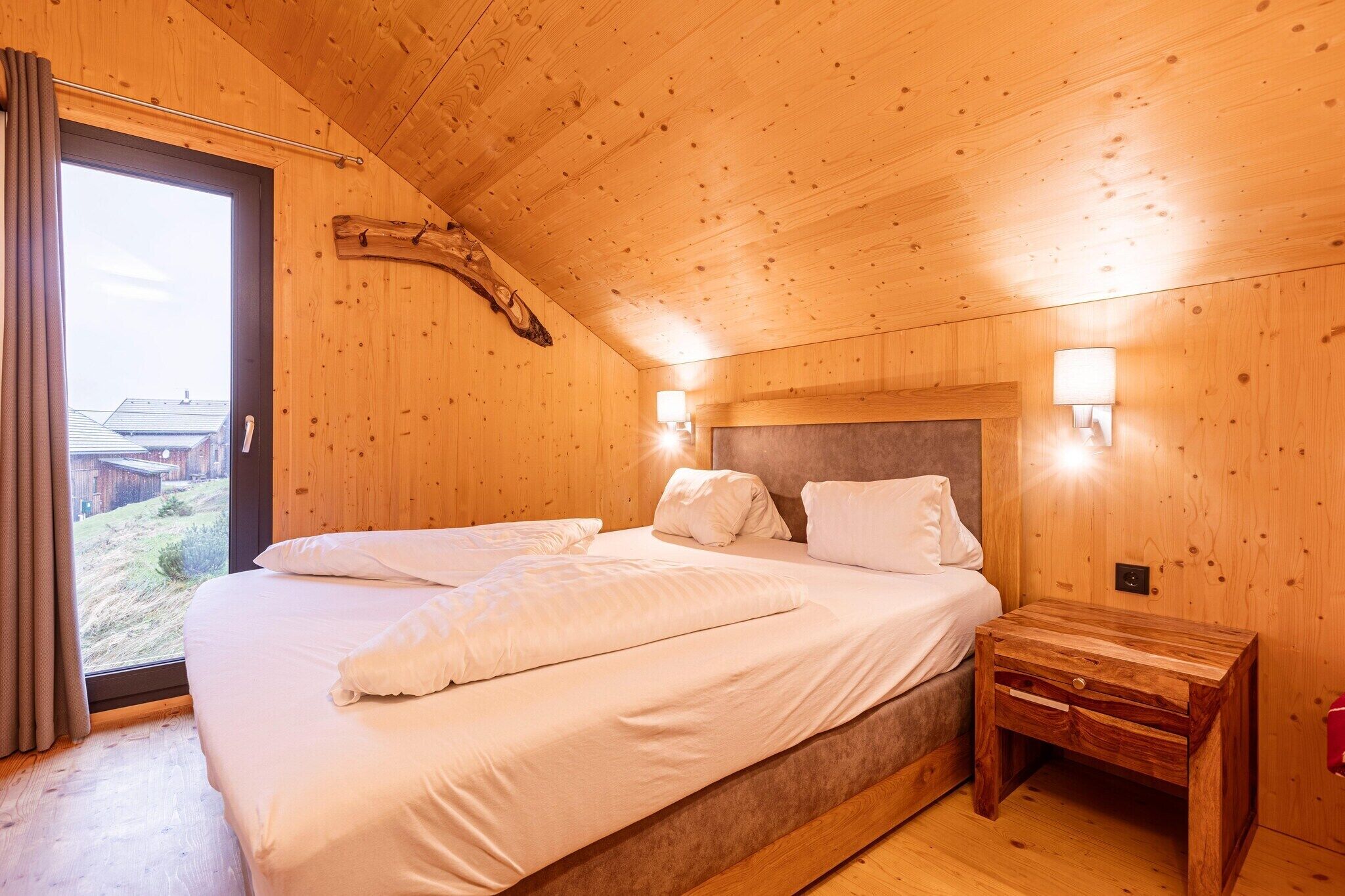 Une pièce en bois avec un lit, une table de chevet et une fenêtre.