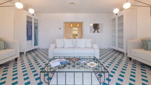Ein modernes Wohnzimmer mit einem weißen Sofa, einem Glastisch und einem gemusterten Boden.
