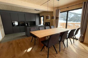 Une cuisine moderne avec des meubles de rangement de couleur sombre, une table à manger en bois et des chaises.