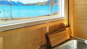 A kitchen with a view of a lake and mountains, wooden walls, and a stainless steel sink. - 5 Person Holiday Home in Oydegard (Tingvoll)