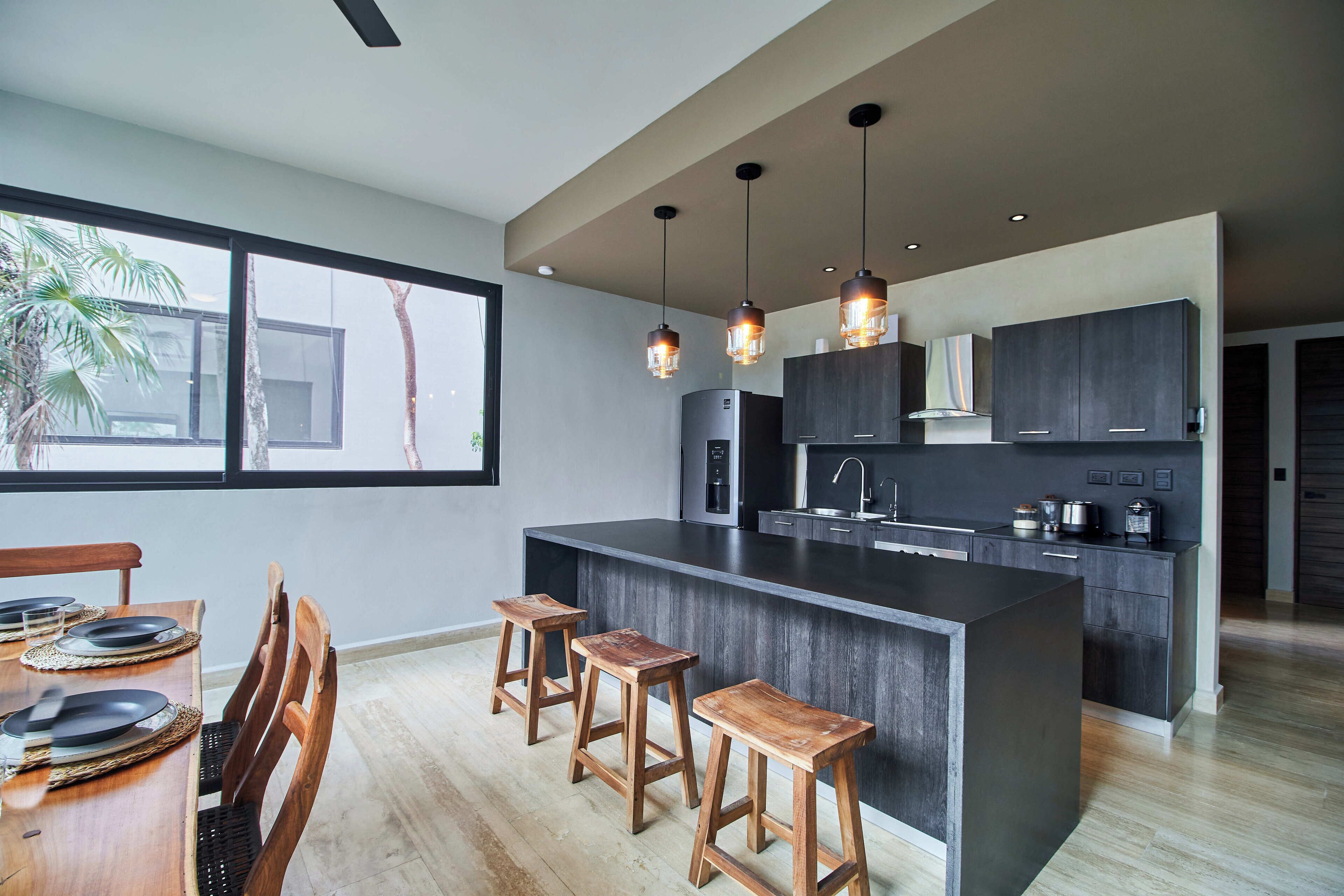 Una cocina moderna con una isla grande, taburetes de madera e iluminación colgante.