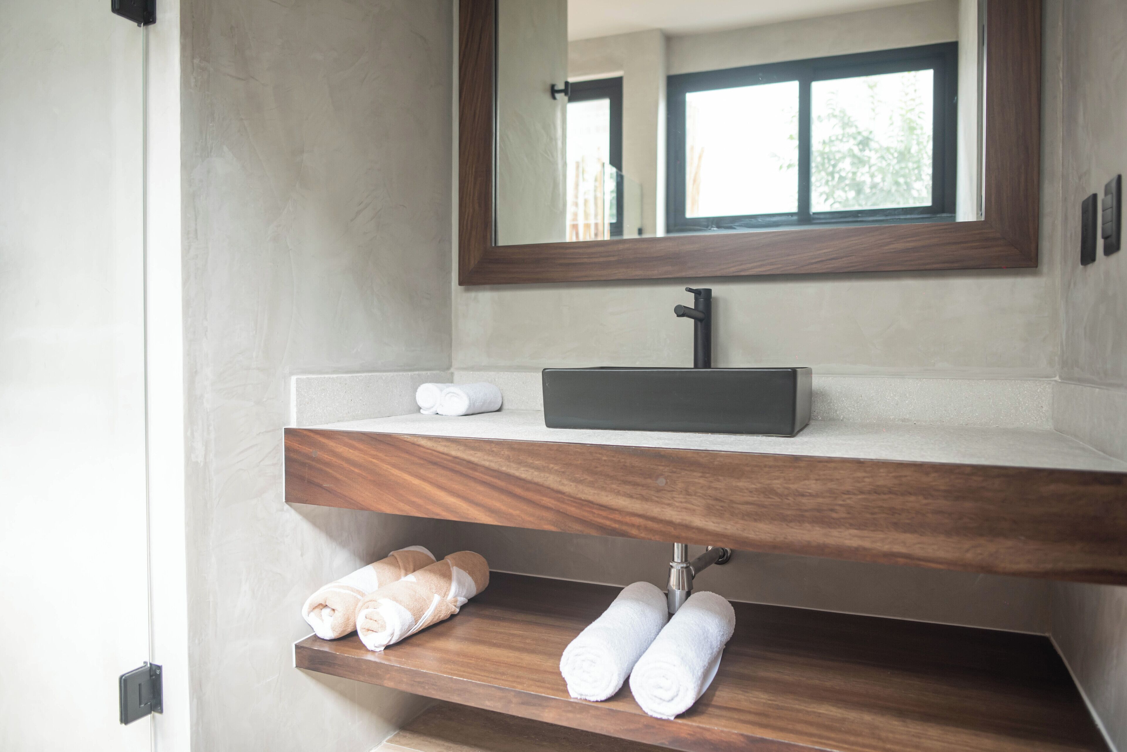 A bathroom with a modern sink, wooden shelves, and a large mirror.