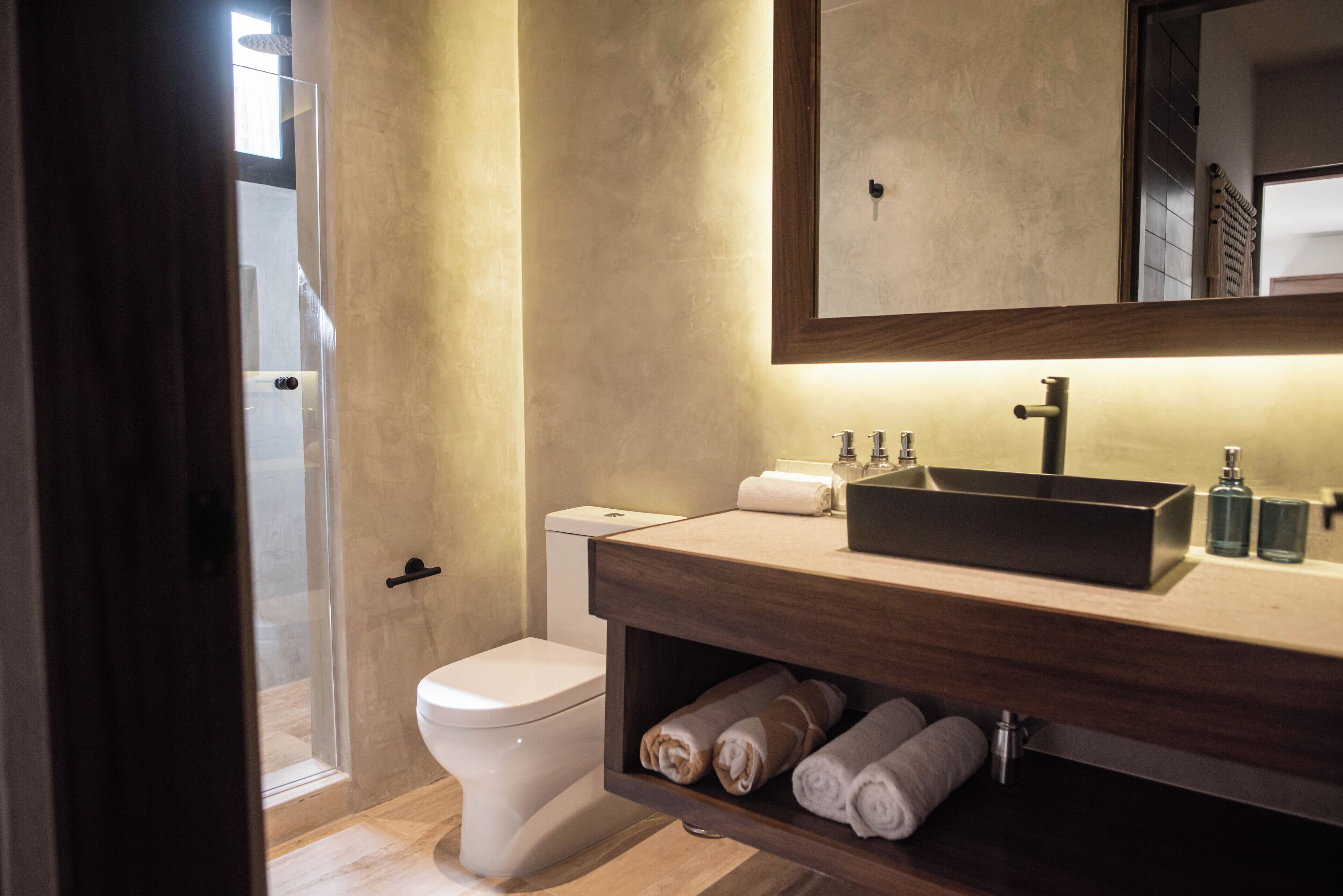 A modern bathroom with a toilet, a sink with a mirror above it, and a shower area.