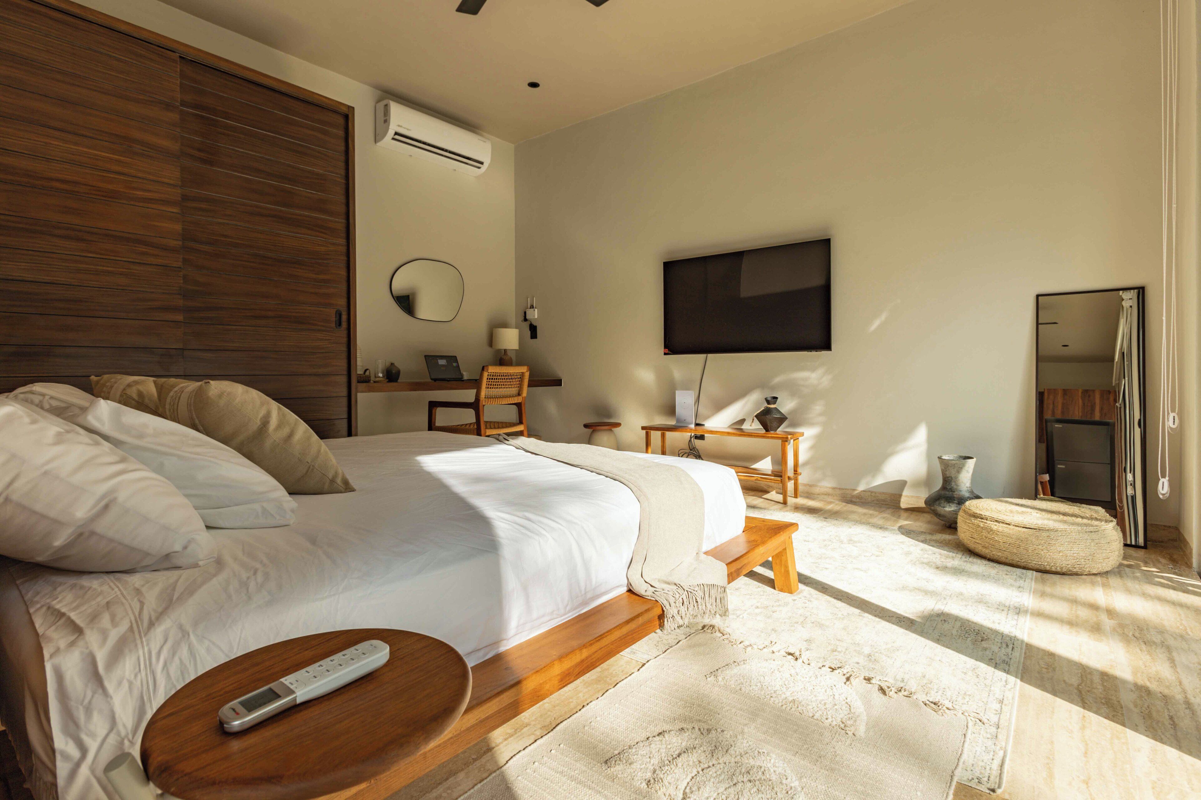 Un dormitorio moderno con una cama grande, mesitas de noche, un televisor y un espejo.